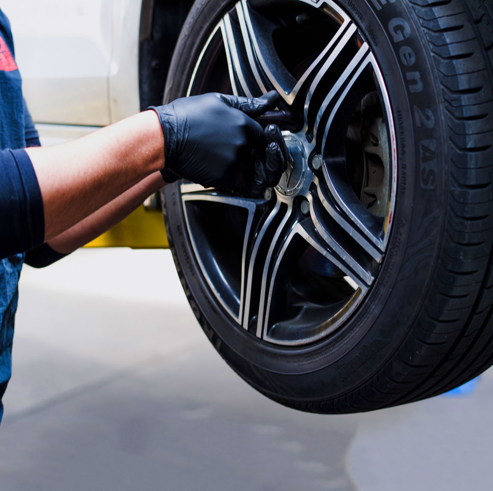 Automotive technician performing hands-on wheel service at Dale's Auto Service