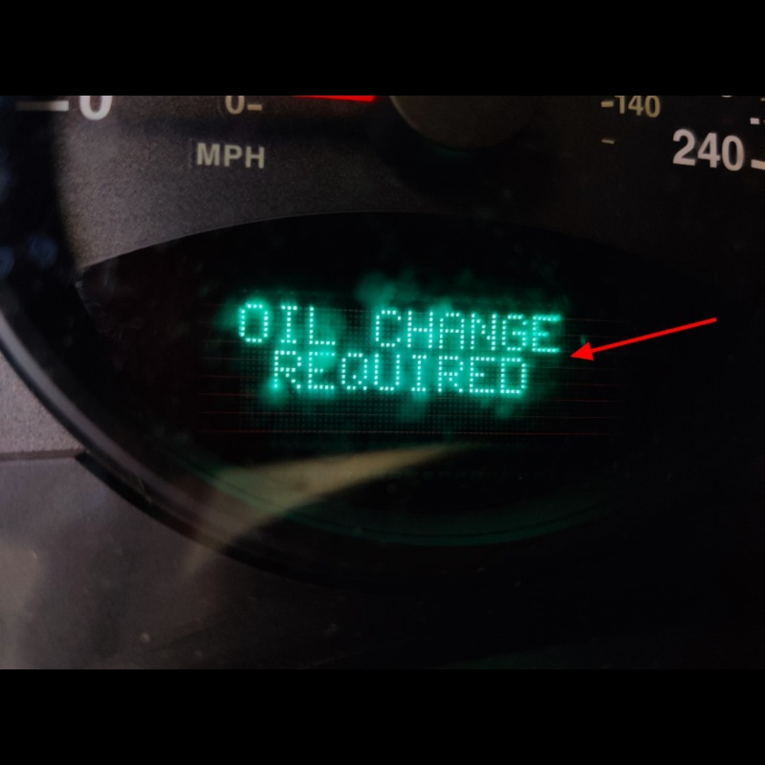 Dashboard warning oil change required displayed in teal on the instrument cluster speedometer in view